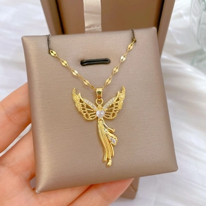 Detailed close-up of a golden angel pendant with sparkling zircons on a beige jewelry pad