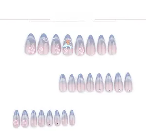 Close-up of almond press-on nails with blue cat-eye gradient, flowers, and 3D charms