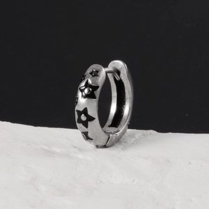 Gros plan d'une boucle d'oreille étoile argentée vintage avec émail noir sur pierre