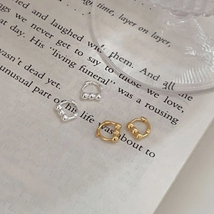 Detail of gold and silver sterling silver hoop earrings with triple bead accents on paper
