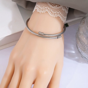 Detail view of silver twisted cable cuff bracelet with open design on a model wrist