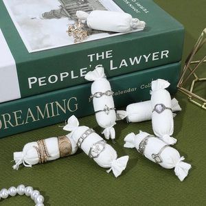 Linen ring display stand featuring gold and silver fashion jewelry on candy-shaped props