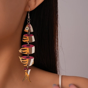 Macro detail of fish-shaped wooden earrings with orange geometric print and metal links