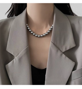 Detail of metallic grey pearl necklace worn by model in a stylish grey blazer suit