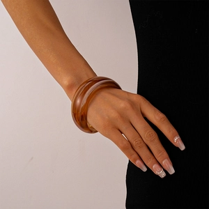 Detailed view of wide amber acrylic resin bangle with vintage marbled texture on wrist