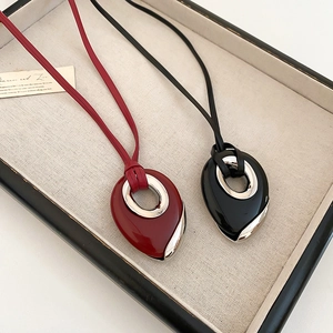 Detail view of teardrop pendants in red and black with polished silver metal accents