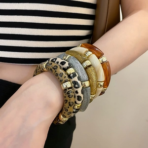 Detail of stacked acrylic bracelets with leopard print, glitter beads and gold spacers