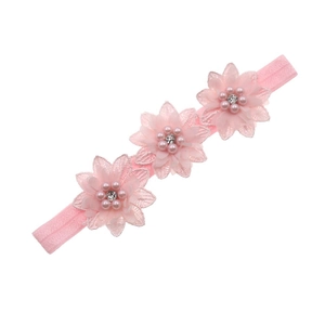 Detail of baby headband featuring three pink lace flowers with pearls and rhinestones