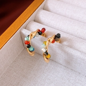 Macro detail of gold-plated geometric earrings with colorful beads in a jewelry box