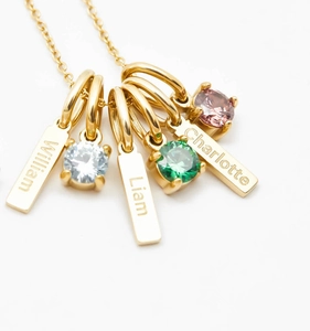 Macro shot of custom engraved name bars and birthstone charms on a gold necklace