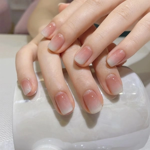 Close-up of nude pink gradient press-on nails in short squoval shape on hands