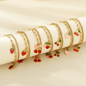 Detailed close-up of double-layer gold bracelets with strawberry and cherry charms