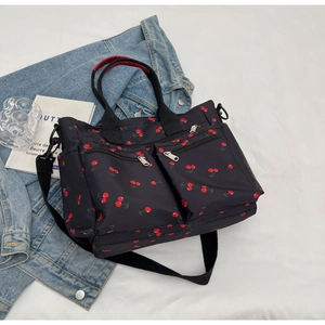 Detail of printed tote bag featuring cherry patterns and multiple functional pockets