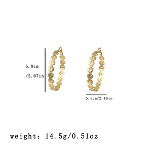 Detail view of large gold sunflower embossed C-shape hoop earrings with size specifications