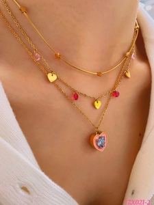 Close-up of a three-layered gold necklace set with colorful heart pendants and blue crystal
