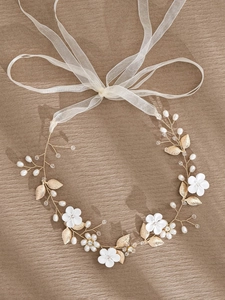 Detail of bridal headband with ceramic flowers, gold leaves, pearls, and organza ribbons