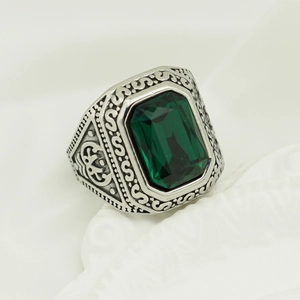 Macro view of vintage silver ring with rectangular green gemstone and scroll patterns
