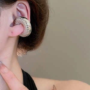 Vue détaillée d'une manchette d'oreille argentée avec une texture de métal martelé sur l'oreille