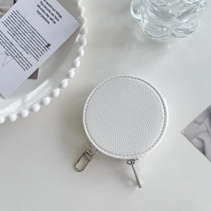 Macro shot of white round coin purse with lychee texture and silver hook on pearl tray