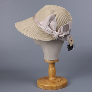 Beige straw sun hat with decorative satin bow on a mannequin head against grey background