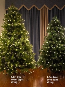 Size comparison of 2.1m and 1.8m faux Christmas trees with warm LED string lights