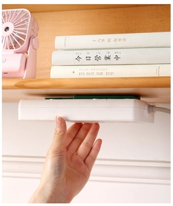 Detail of sliding socket fixer mounted under wooden shelf for home cable management