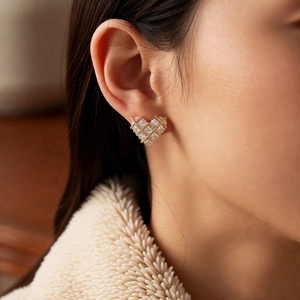 Detailed view of gold plated heart stud earrings with cubic zirconia on a model ear