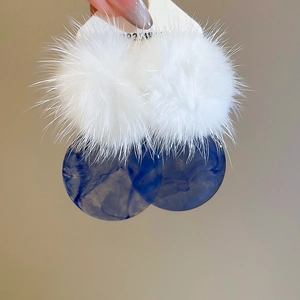 Detail of fluffy white pom-poms and blue marble resin earrings with S925 silver posts