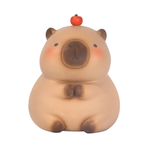 Tirelire Capybara avec pomme rouge sur la tête en position assise, fini mat