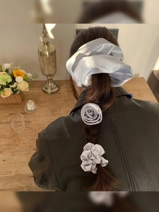 Detail of light gray satin flower hair tie and scrunchie set styled on a braided ponytail