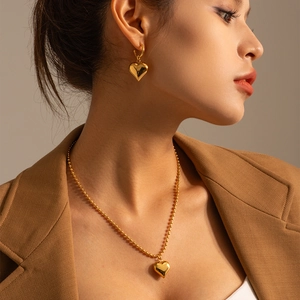 Close-up of model wearing a vintage 18k gold-plated heart pendant and bead chain necklace