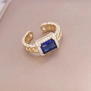 Macro detail of a square blue zircon ring with gold-plated hollow chain band design