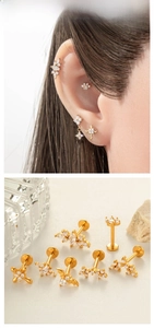 Détail de clous labret dorés avec zircons en formes de chauve-souris, croix et fleurs
