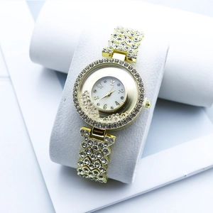 Close-up of gold women's watch with crystals and mother of pearl dial on display