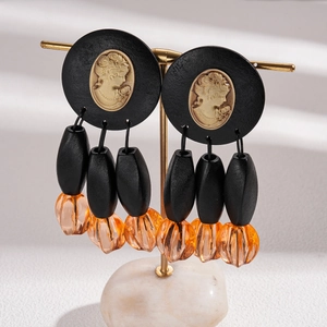Detail of vintage acrylic cameo earrings with orange pumpkin beads and black charms