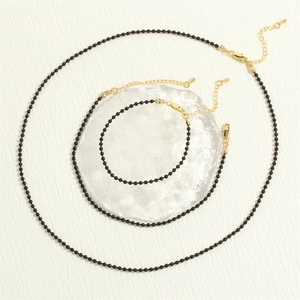 Detail of black bead necklace and bracelet set with adjustable gold lobster clasps