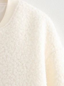 Close-up of the textured off-white sherpa fleece fabric and ribbed neckline detail