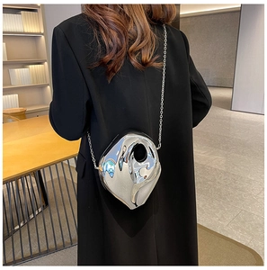 Close-up of a silver heart-shaped acrylic bag with a metallic chain on a black coat
