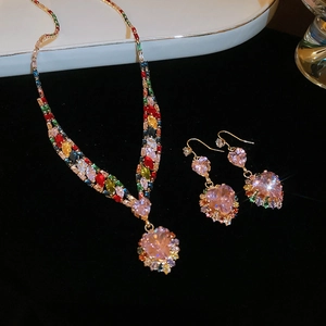 Detailed view of luxury gold necklace and earrings set with pink zircon heart pendants