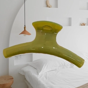 Translucent olive green 15cm hair claw clip shown in a minimalist bedroom setting