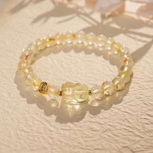Detail of yellow quartz beaded bracelet with gold coin charm on textured surface