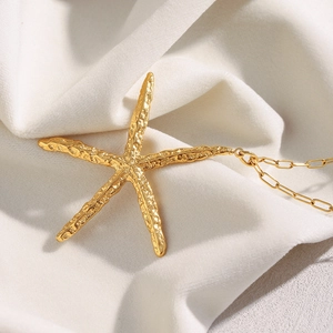 18K gold plated stainless steel starfish necklace with hammered texture on white fabric
