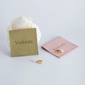 Macro shot of gold geometric pearl earrings with velvet jewelry pouches on a white shell