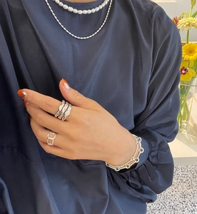 Detail showing layered 925 silver rings and a blue gemstone bracelet on model