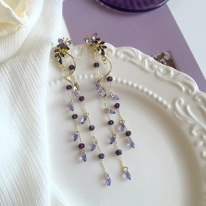 Gros plan sur les boucles d'oreilles papillon glycines violettes à longs pompons
