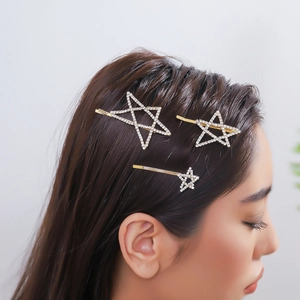 Set of three golden pentagram hairpins with rhinestones worn by a model in profile