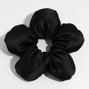 Detailed macro view of the black satin flower hair tie with a smooth silky texture and petals