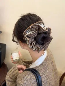 Detail of oversized retro brown plaid scrunchie with delicate white lace edging