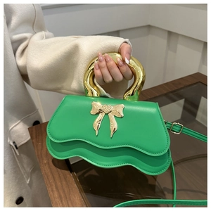 Detail of green PU leather handbag featuring wave-shaped bottom and gold metal handle
