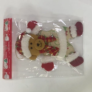 Detailed view of plush Christmas bear hanging ornament inside clear polybag packaging